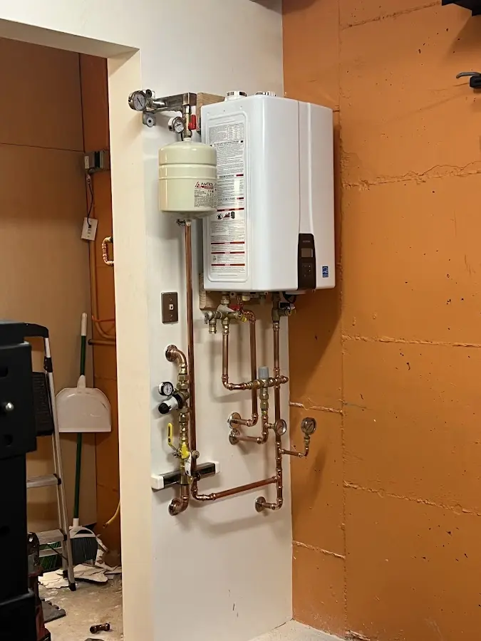 Plumbing technician inspecting water heater connections in Gilmanton